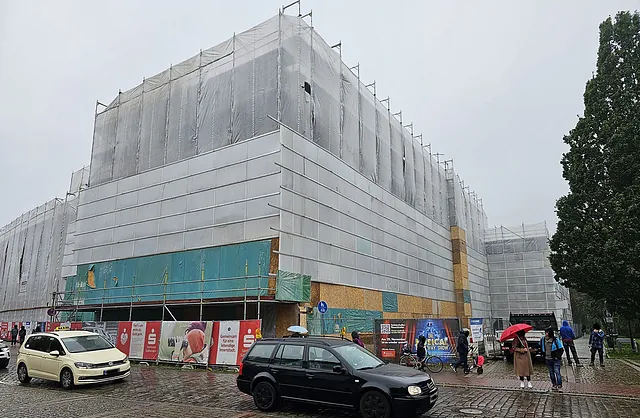 Eingerüstetes Gebäude der Sparkasse Neumünster mit weißer Schutzverkleidung und Fassadengerüst von VVV Gerüstbau für umfangreiche Sanierungsarbeiten.