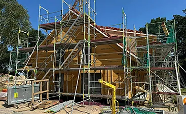 Mehrgeschossiges Baugerüst rund um einen Holzhaus-Neubau für sichere Dach- und Fassadenarbeiten durch ein Gerüstbauunternehmen im Raum Hamburg.