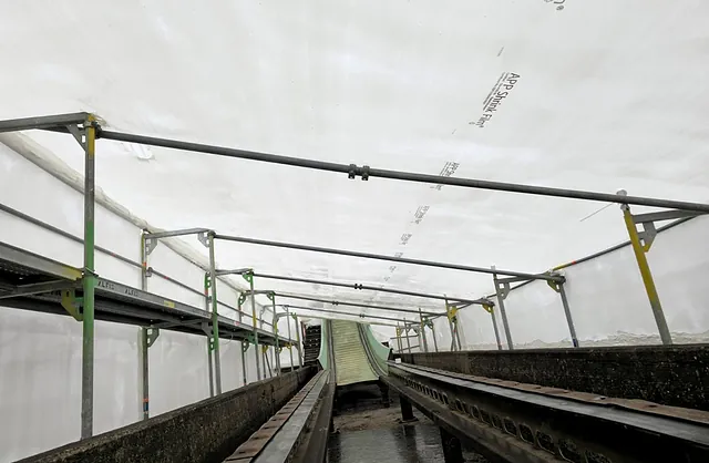 Innenansicht einer eingehausten Wasserbahn im Heide Park Soltau mit Gerüstkonstruktion und weißer Schutzfolie für wettergeschützte Wartungsarbeiten.