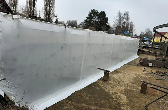 Großflächige Schutzeinhausung aus weißer Folie entlang einer Wasserbahn im Heide Park Soltau, Spezialgerüstbau von VVV Gerüstbau.