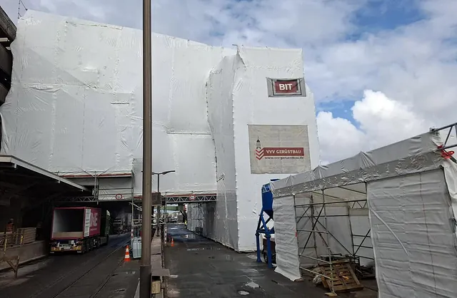 Großflächige, weiß eingehauste Industrieanlage mit Gerüstkonstruktion von VVV Gerüstbau für geschützte Sanierungsarbeiten im Hafenbereich.