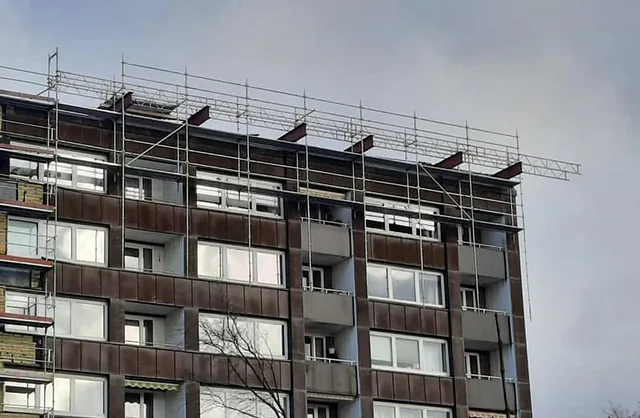 Mehrgeschossiges Wohnhaus mit Fassadengerüst und Dachfanggerüst für Sanierungs- und Dacharbeiten in Norderstedt, Schleswig-Holstein.